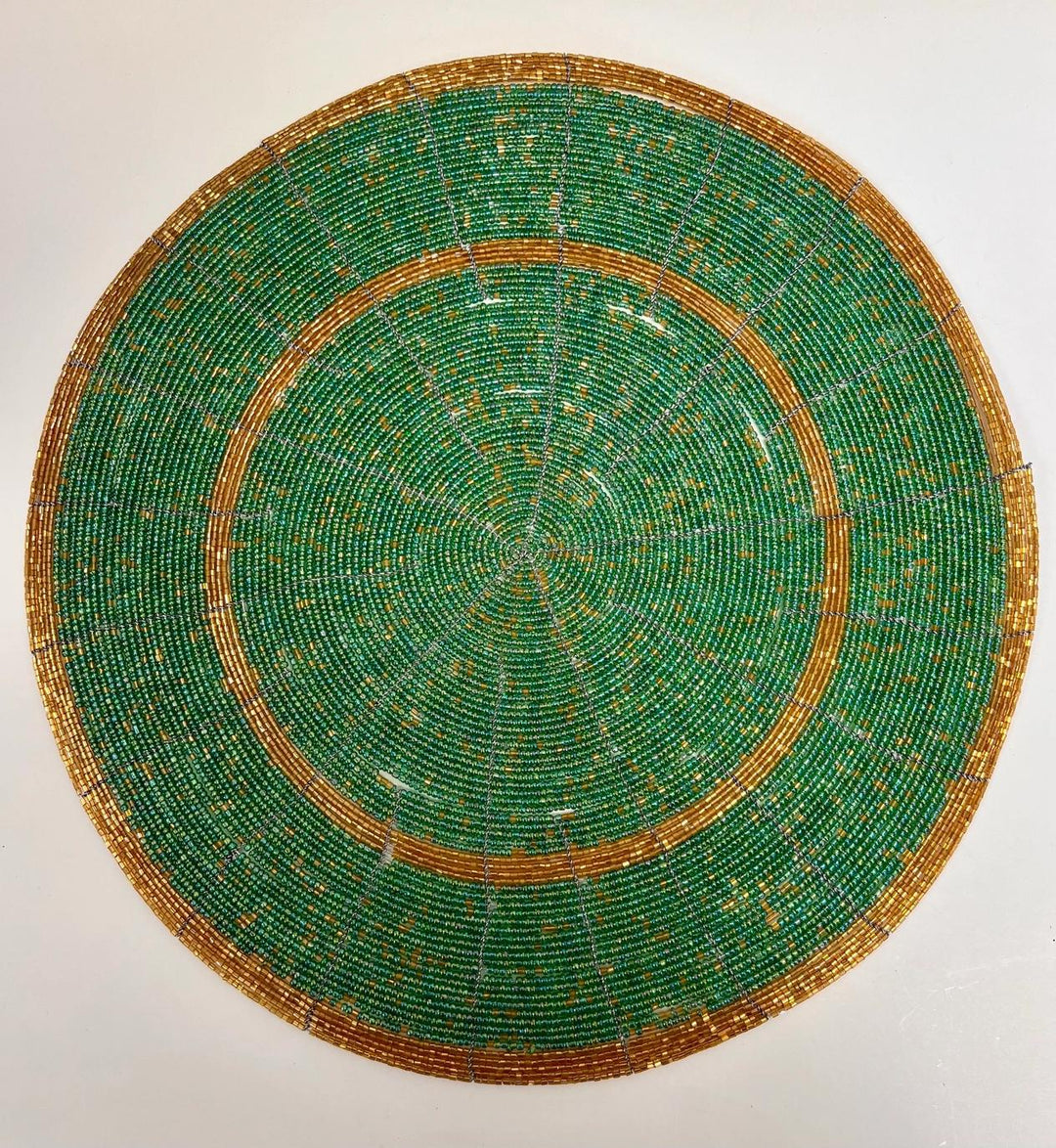Round green and gold beaded plate on a white background