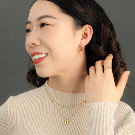 Woman wearing gold jewelry against a neutral background