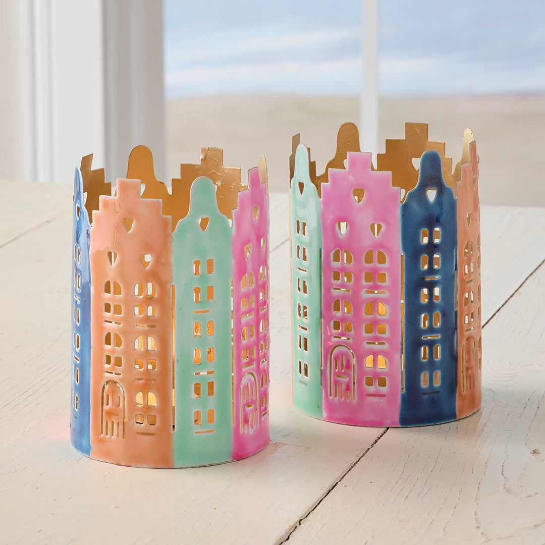 Colorful ceramic Dutch cityscape candle holders on a light surface with a blurred outdoor background.