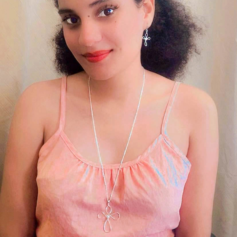 Woman wearing silver cross necklace and matching earrings