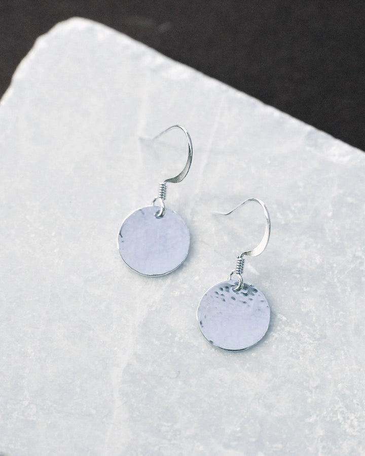 Silver textured round earrings on a white surface