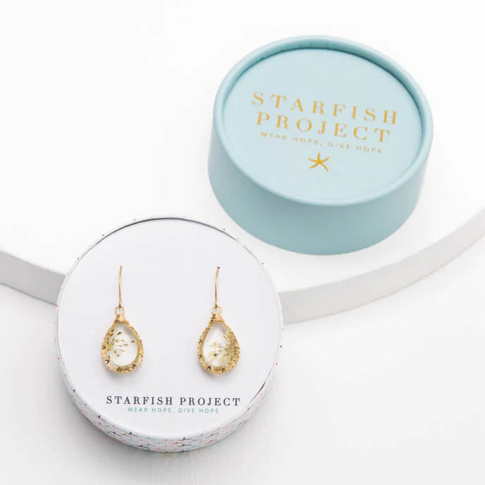 Gold earrings in a 'Starfish Project' jewelry box on a white background