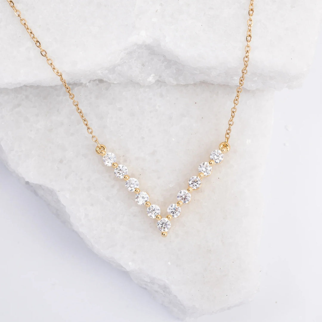 Gold necklace with clear stones on a marble surface