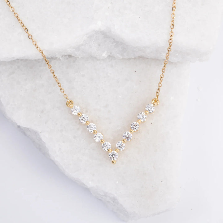 Gold necklace with clear stones on a marble surface