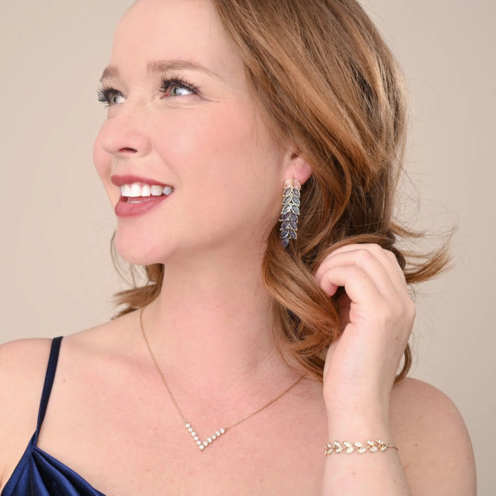 Woman wearing earrings and a necklace, smiling against a beige background