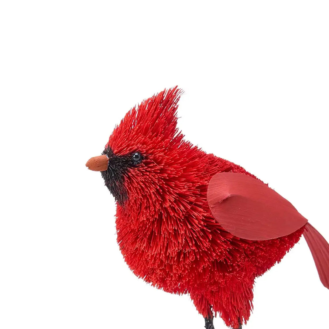 A bright red cardinal bird figurine with textured, brush-like feathers, a black face, and a small orange beak, shown against a plain white background.