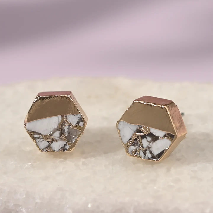 A hexagon gold earring with white turquoise on a white background