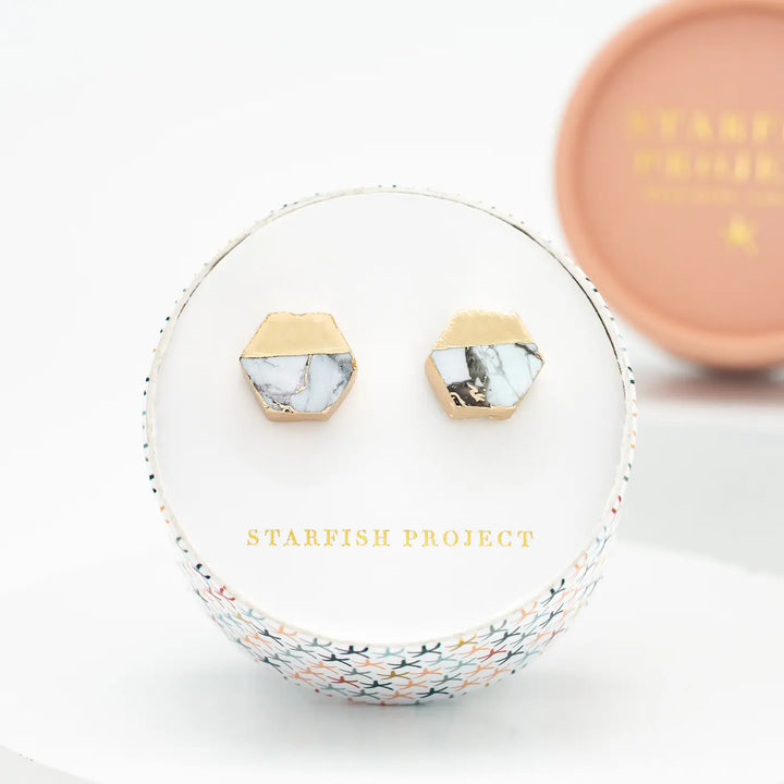 A hexagon gold earring with white turquoise in a Starfish Project box