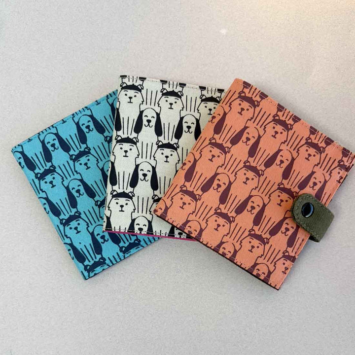 Three patterned wallets with dog designs on a light fabric gray background
