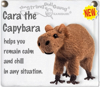 A capybara string doll labeled 'Cara the Capybara' on a white sign-style background with text reading 'helps you remain calm and chill in any situation.' and a yellow 'NEW' badge.