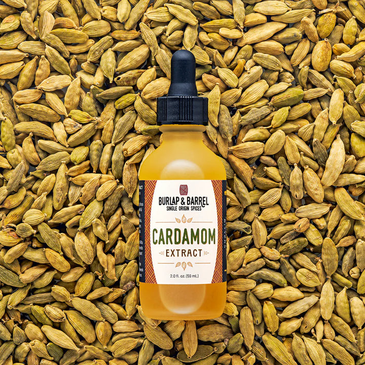 Bottle of Burlap & Barrel Cardamom Extract surrounded by cardamom pods