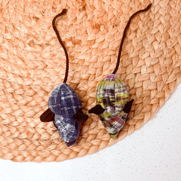 Two fabric catnip mice on a woven mat