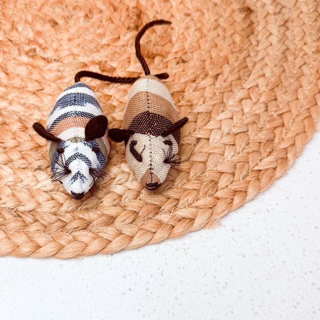 Two toy mice on a woven mat