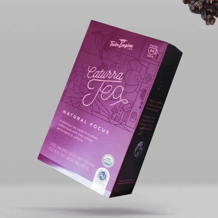 Purple packaging of Caturra Tea with brand logo on a gray background