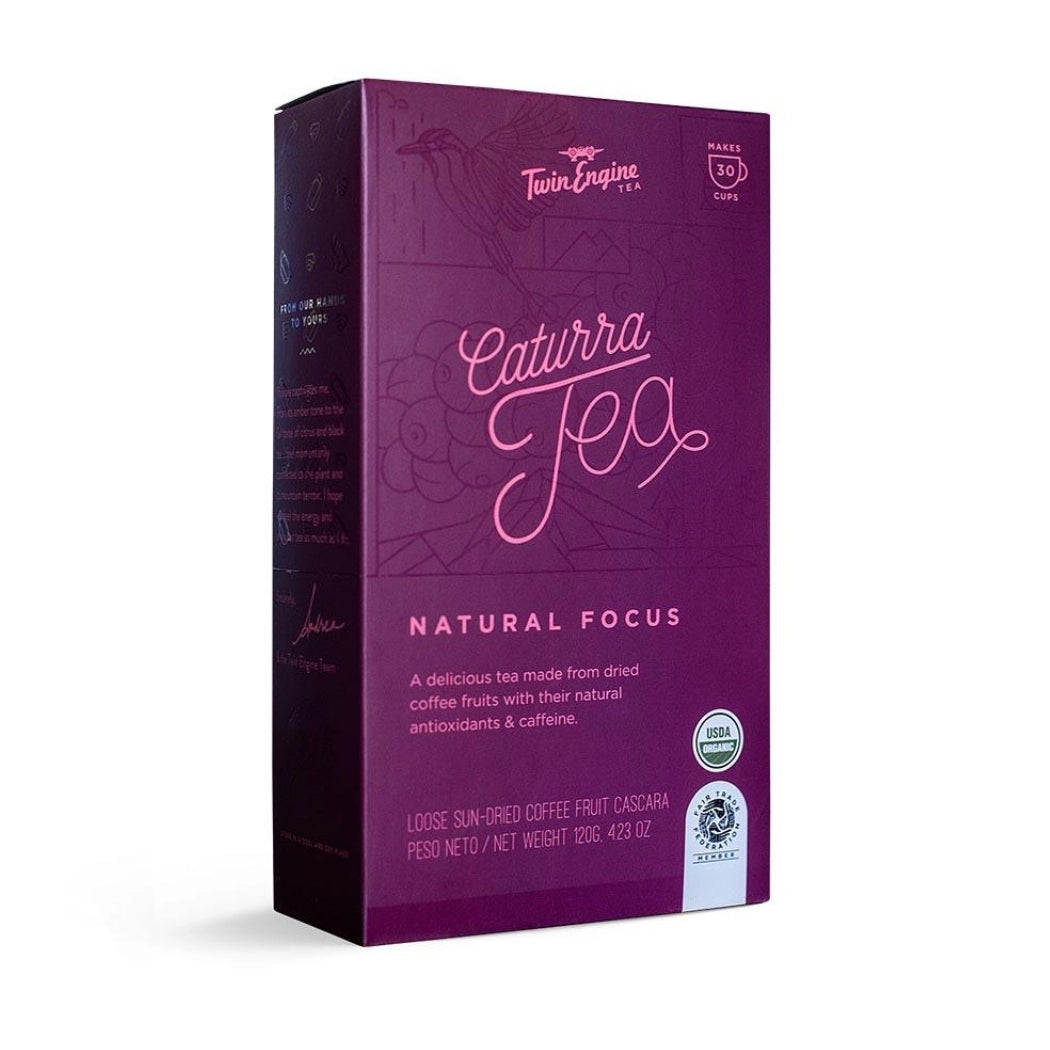 A box of Twin Engine Tea Catura Tea Natural Focus loose-leaf coffee fruit casava tea, shown at a three-quarter angle on a white background.