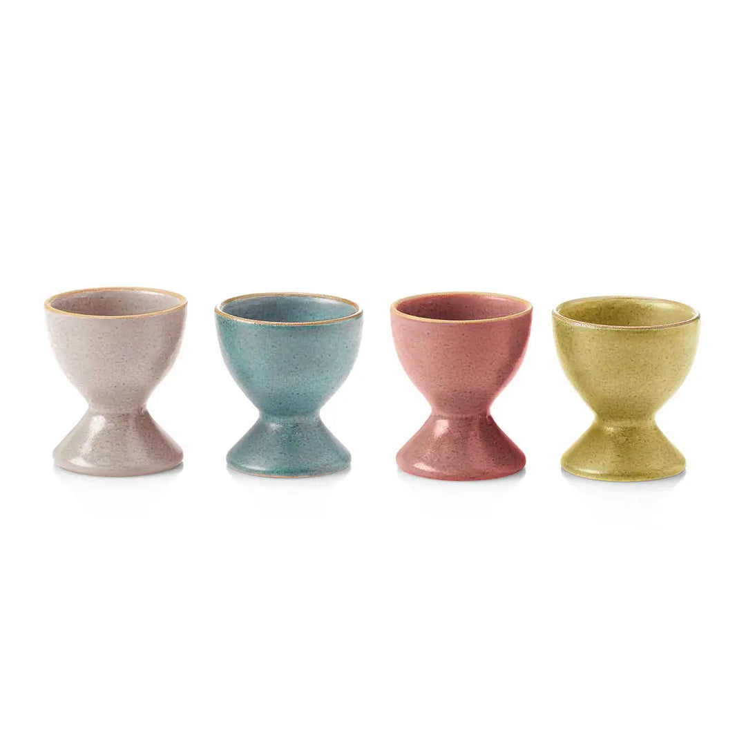 Four ceramic egg cups in different colors on a white background