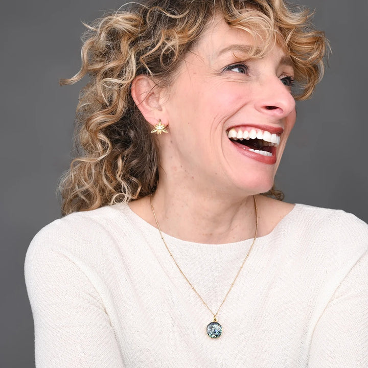 Woman wearing a necklace with a pendant against a gray background