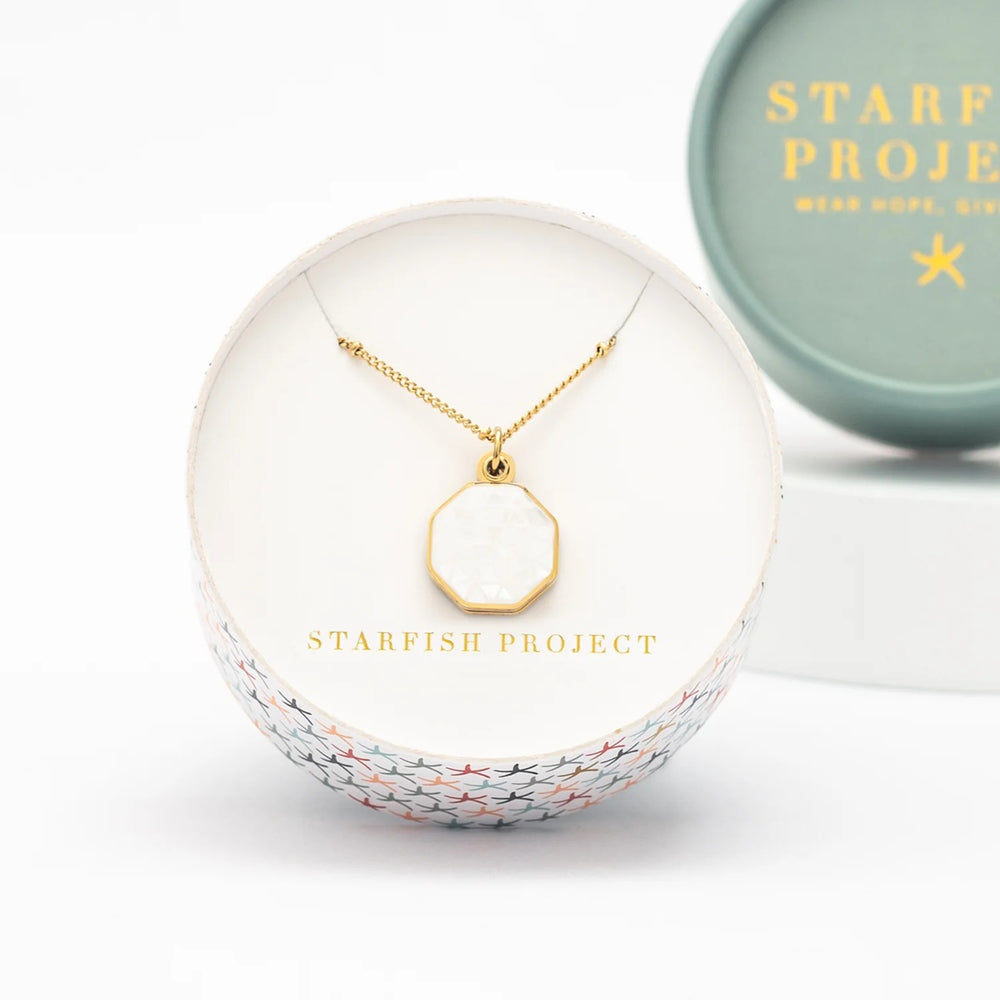 Gold necklace in a white jewelry box with 'Starfish Project' branding.