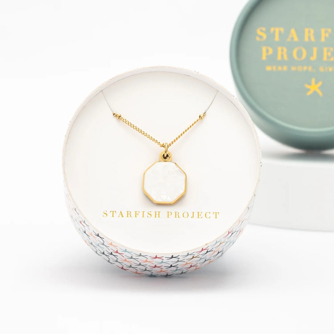 Gold necklace in a white jewelry box with 'Starfish Project' branding.