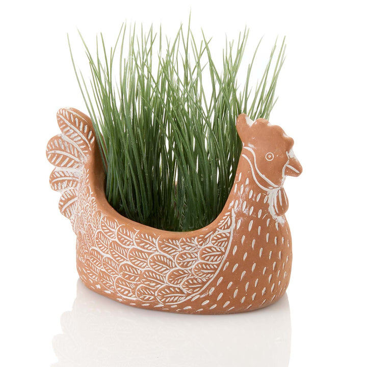 Ceramic chicken planter with green grass on a white background