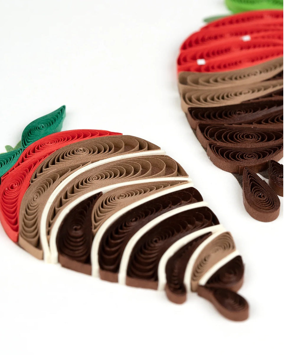 Quilled strawberry decorations with red and green leaves on a white background