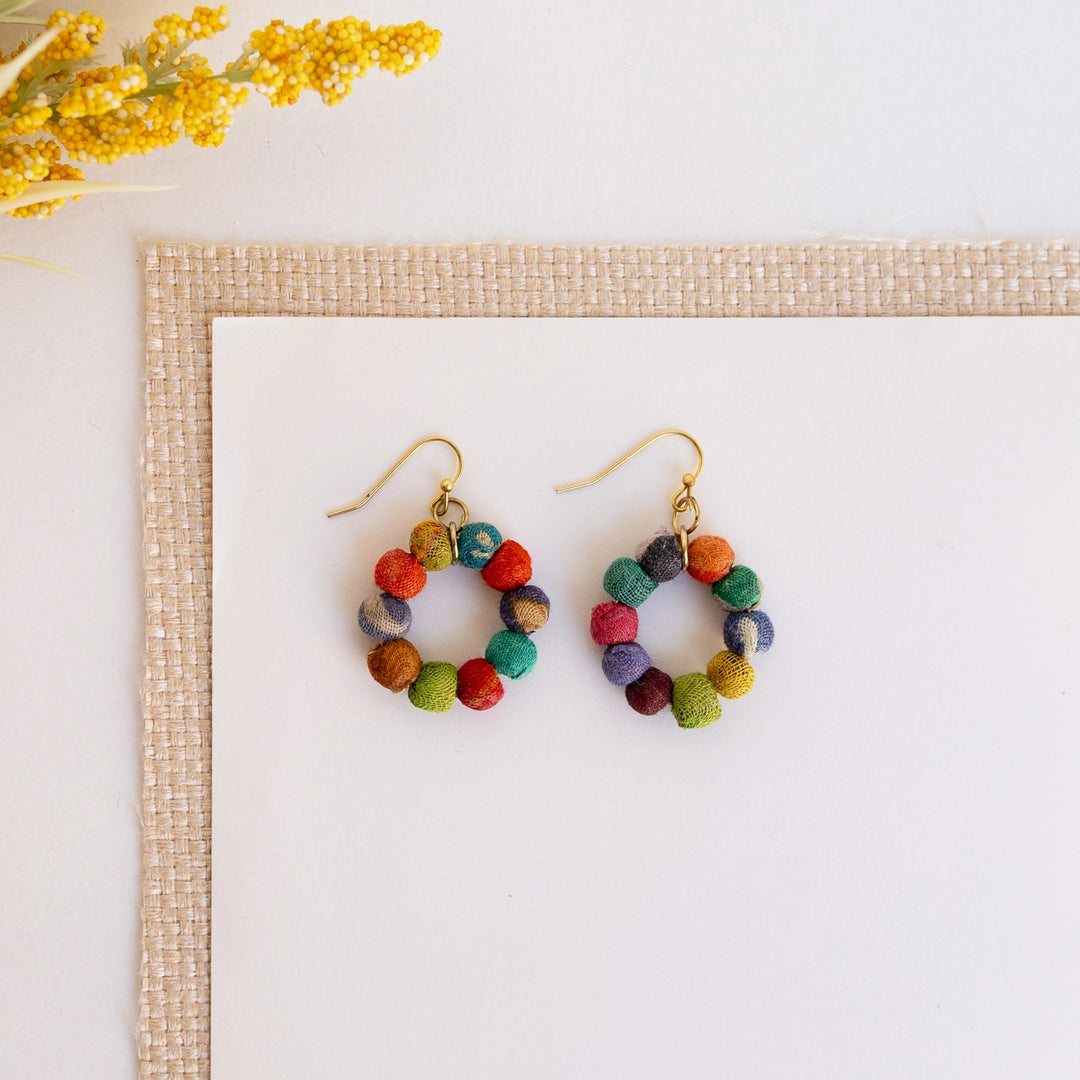 Colorful Kantha petite hoop earrings on a white background with a beige border and yellow flowers.