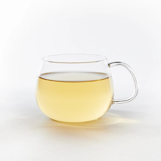 Clear glass mug filled with coconut green tea on a white background