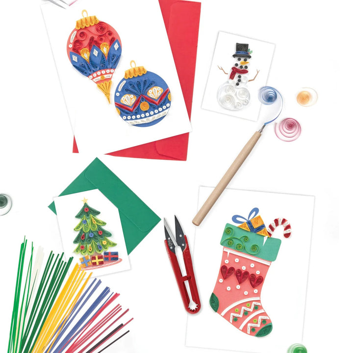 Colorful Christmas-themed craft items including cards, paper strips, and tools on a white background.