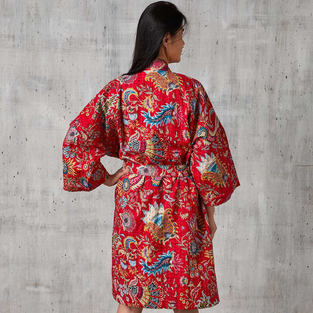 The back of a woman wearing a crimson paisley kantha robe. 