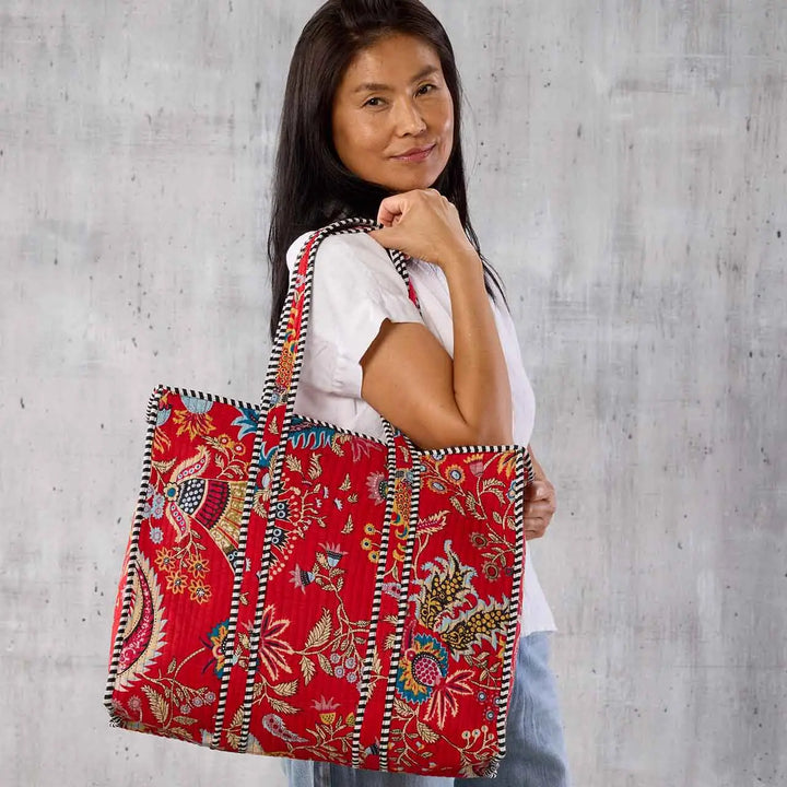 a woman carrying a crimson paisley large quilted tote. 