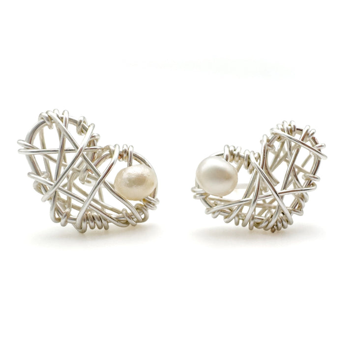 Pair of silver heart-shaped earrings with pearl-like beads on a white background