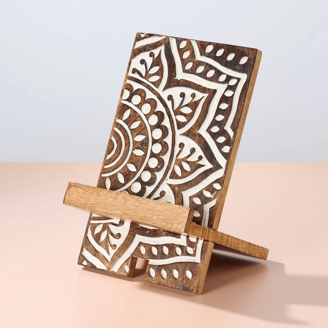 Wooden tablet stand with intricate carved white patterns on a wood background