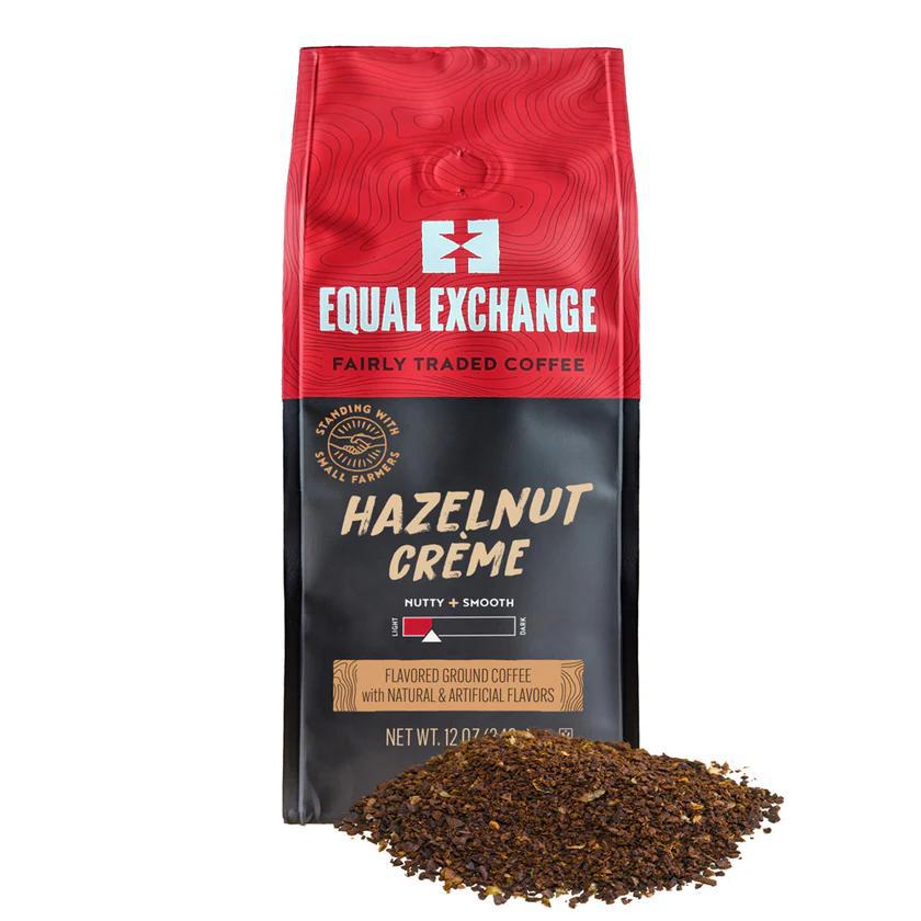 A bag of Equal Exchange Hazelnut Creme ground coffee with a pile of ground coffee in the foreground, under a red and black label.