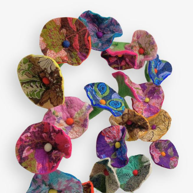 Multicolored felt flowers arranged in a circular pattern on a white background