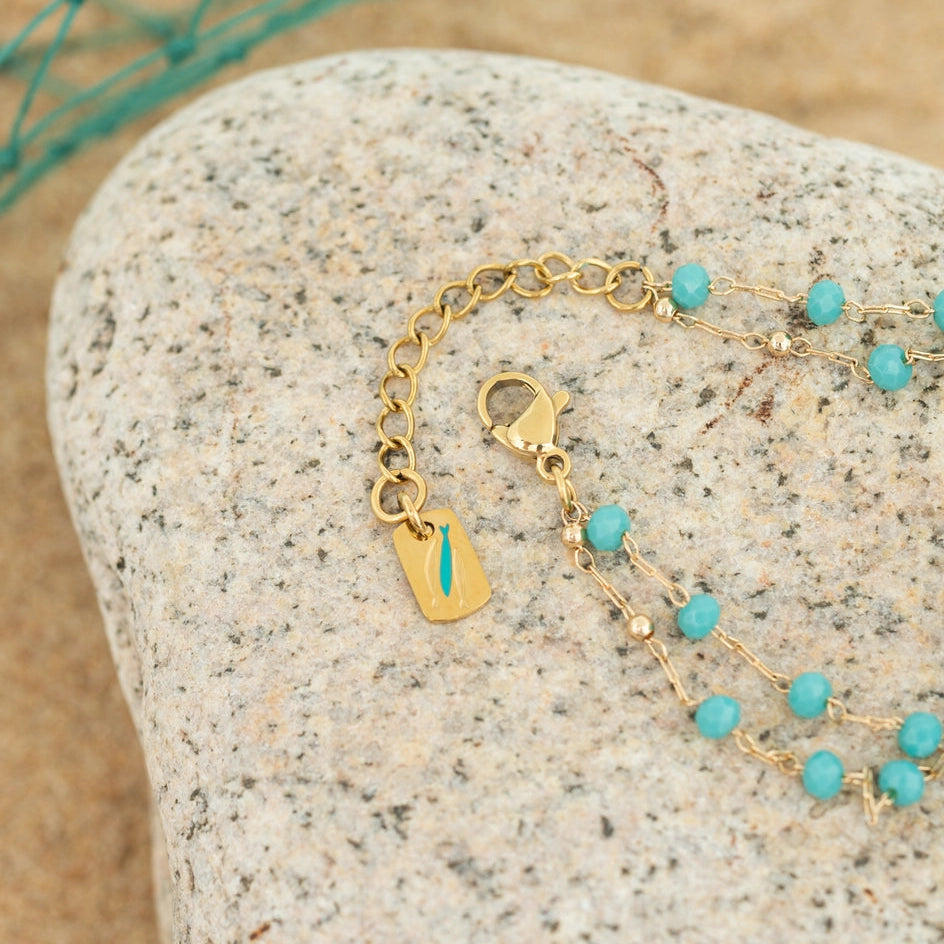 Gold bracelet with turquoise beads on a textured stone surface