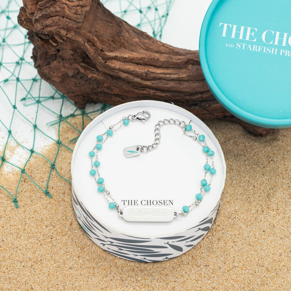 bracelet with turquoise beads on a branded box, surrounded by natural elements.