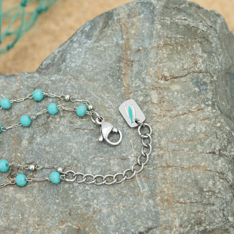 Turquoise beaded bracelet with silver chain on a rock