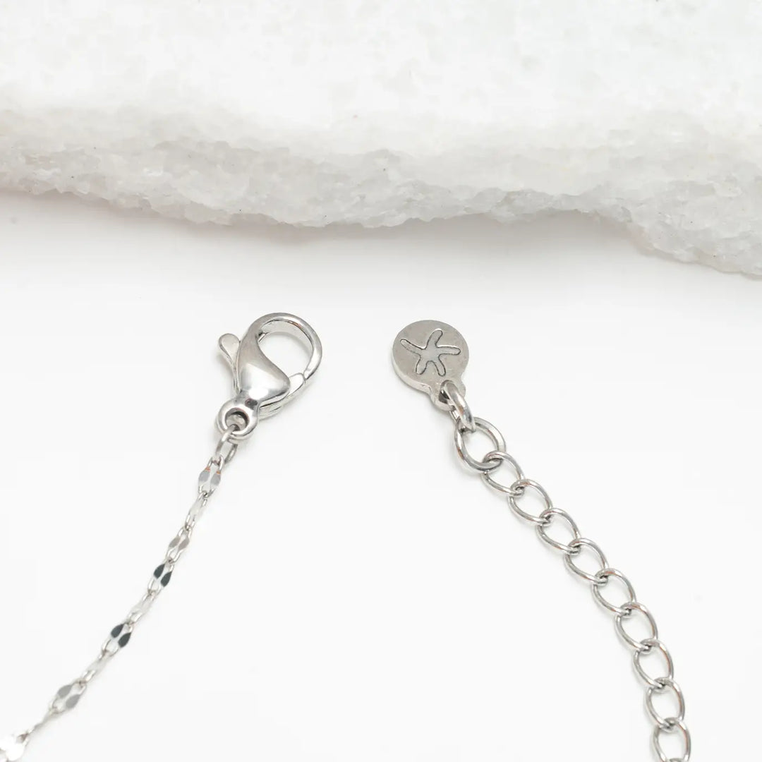 Close-up of a silver necklace chain with clasp on a white background