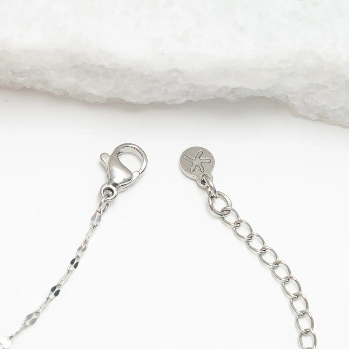 Close-up of a silver necklace chain with clasp on a white background