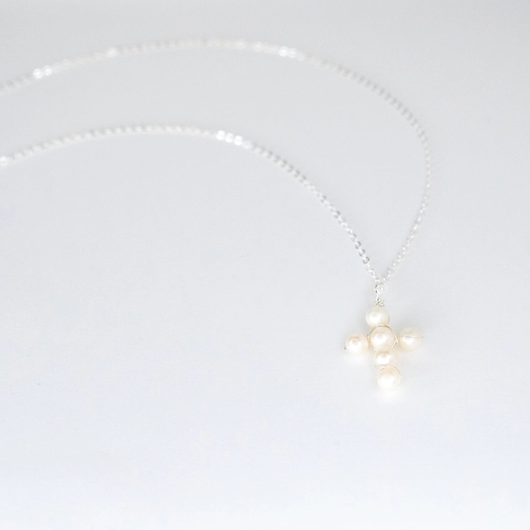 Pearl necklace with silver chain and metal on a light gray background