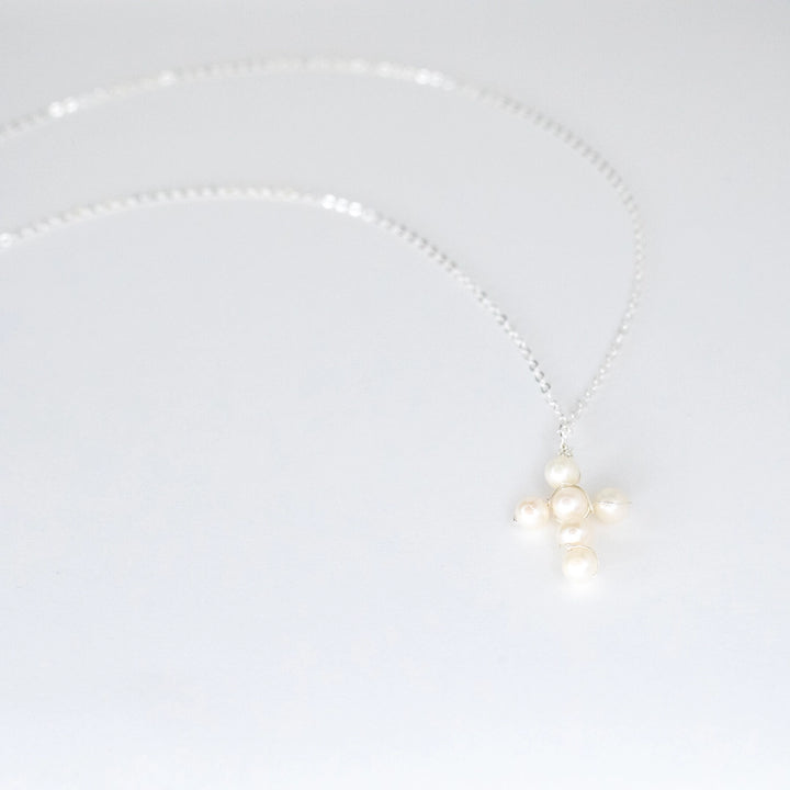 Pearl necklace with silver chain and metal on a light gray background