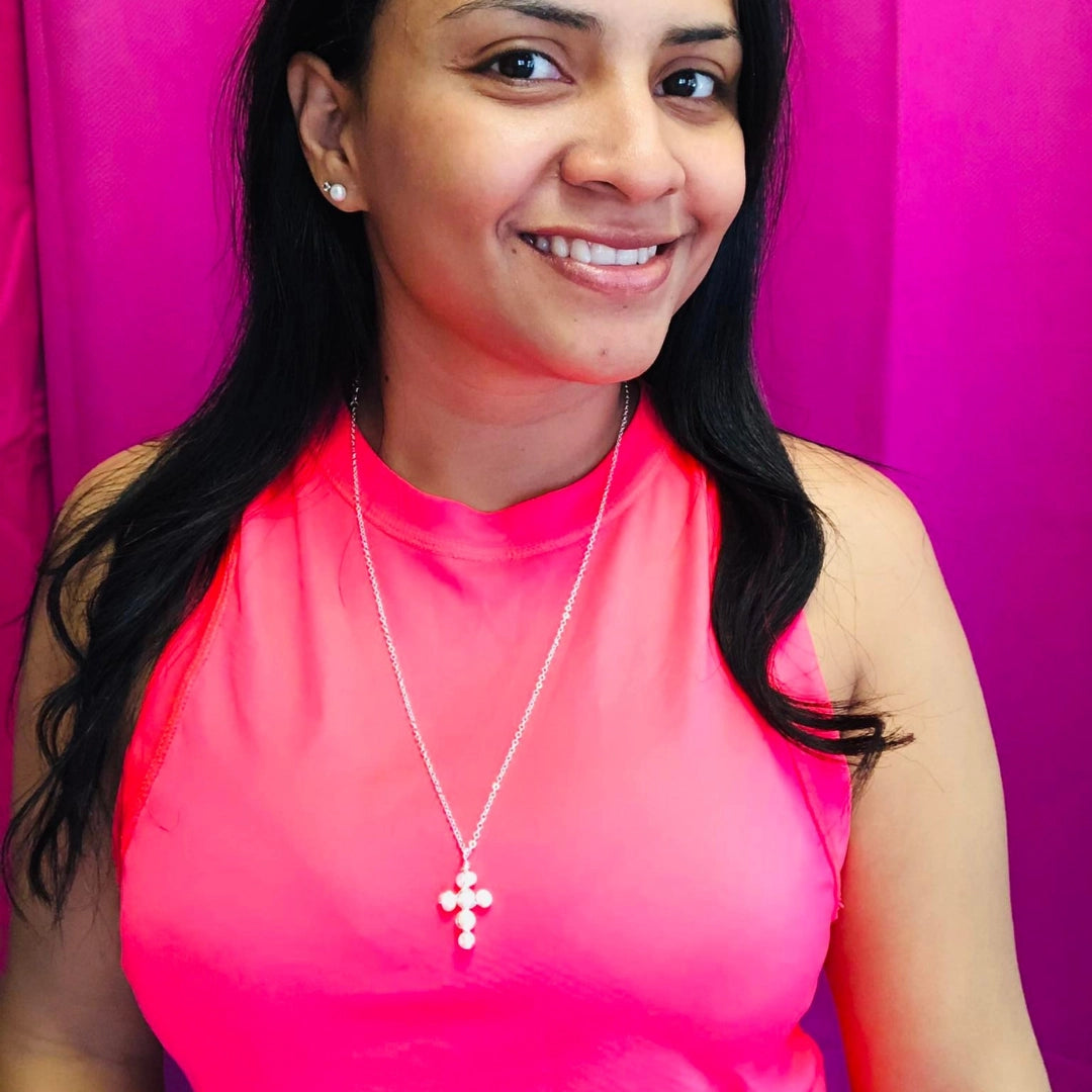 Woman wearing pearl cross necklace on a silver chain
