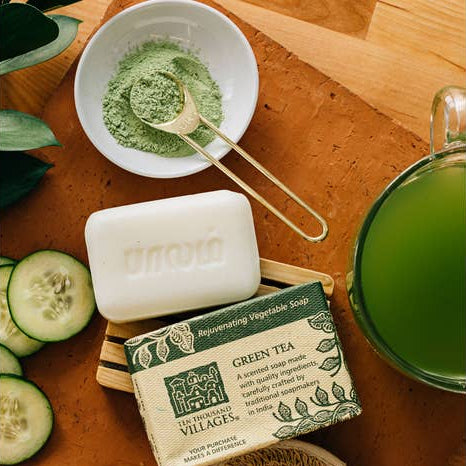 Hand-crafted green tea scented soap and packaging on table with cucumbers and green tea.