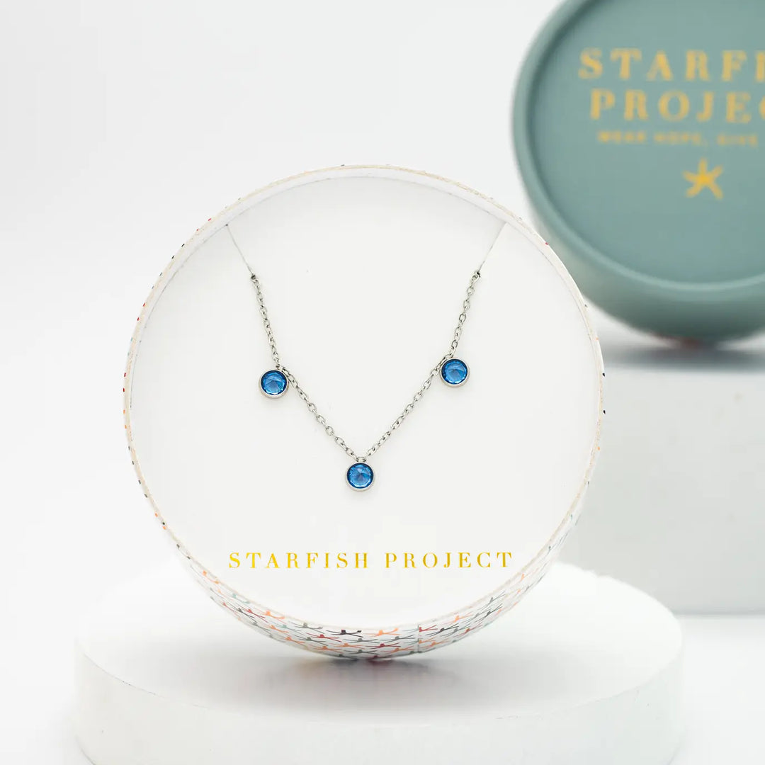 A silver necklace with blue stones in a Starfish Project box.
