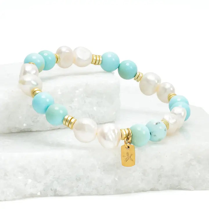 Bracelet with turquoise and white beads on a textured white surface