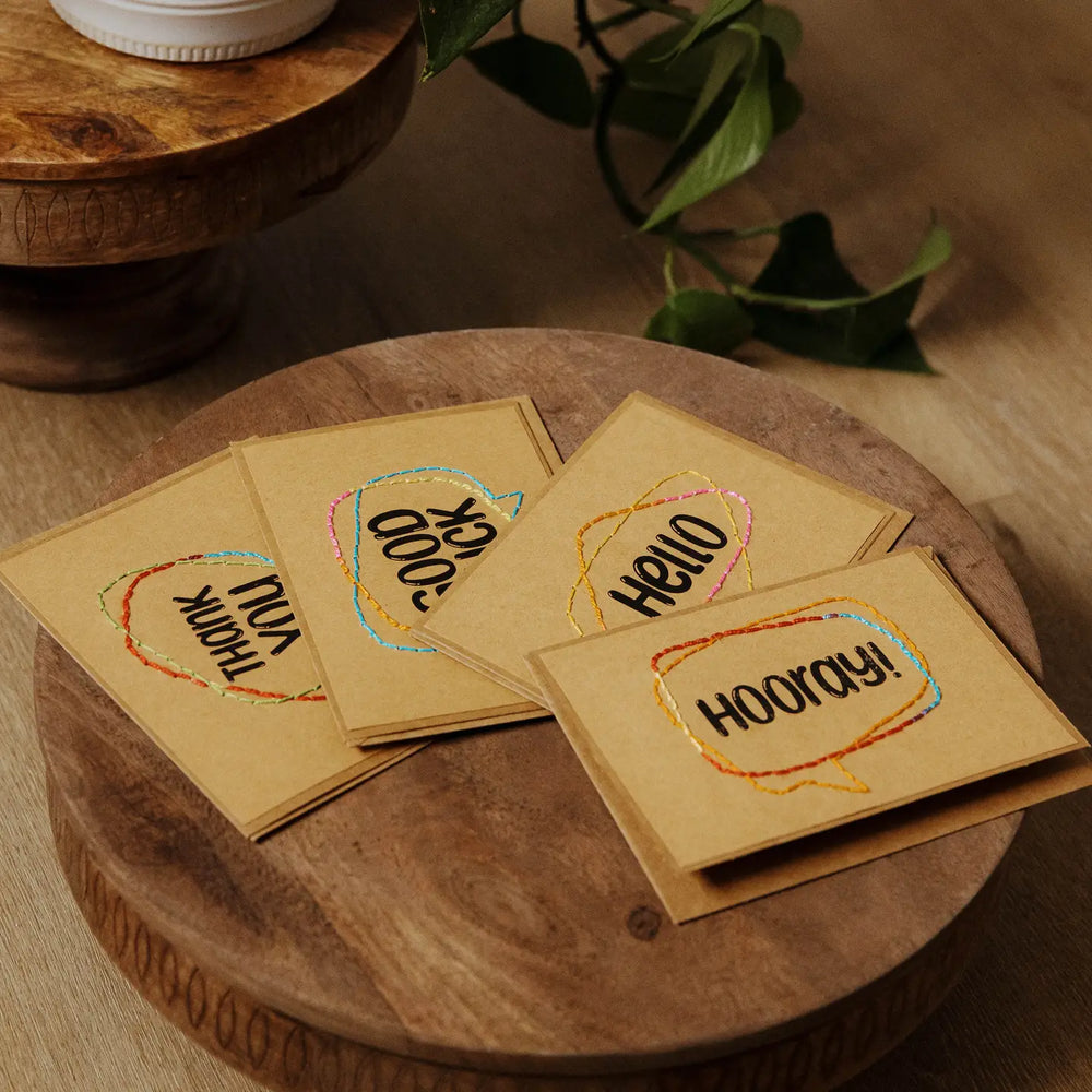 Set of embroidered cards with text on a wooden surface