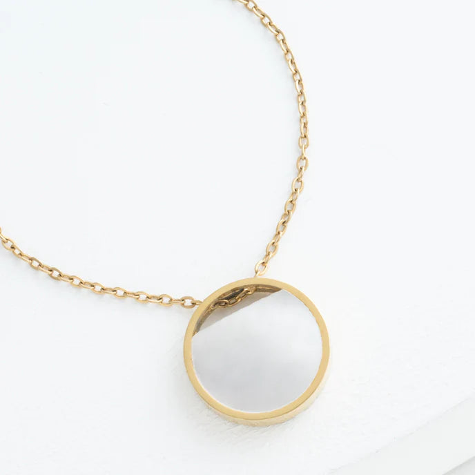 Gold necklace with a round pendant on a white background