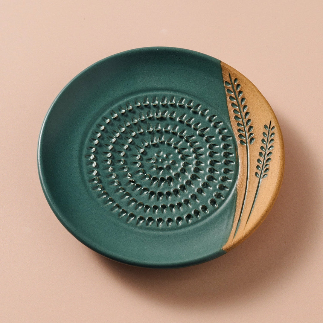 Ceramic grater plate with green and beige design on a beige background