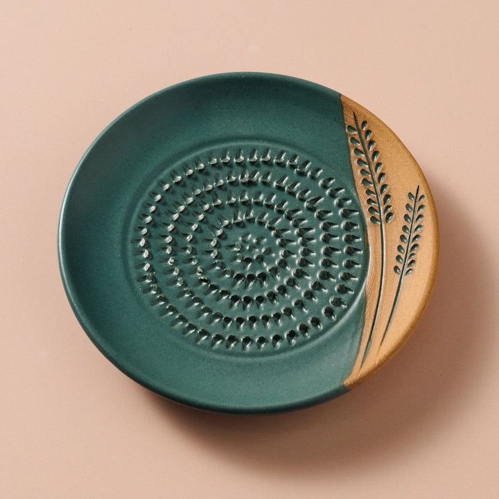 Ceramic grater plate with green and beige design on a beige background