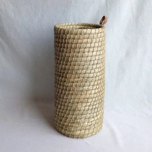 Woven cylindrical basket with a loop on a white background
